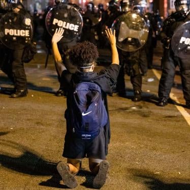 A demonstrator kneels facing a police line in front of the White House while protesting the police killing of George Floyd. Washington, DC, May 31, 2020. 