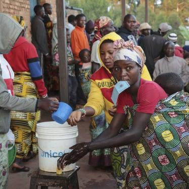 A voter holds her identity card in her mouth as she washes her hands before casting her vote in the presidential election, in Giheta, Gitega province, Burundi, on May 20, 2020.