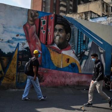 People wearing face masks walk past a mural depicting Venezuelan president Nicolas Maduro in Caracas on April 17, 2020, amid the novel coronavirus (COVID-19) outbreak