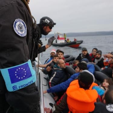 Frontex coast guards talking to group of migrants on boat