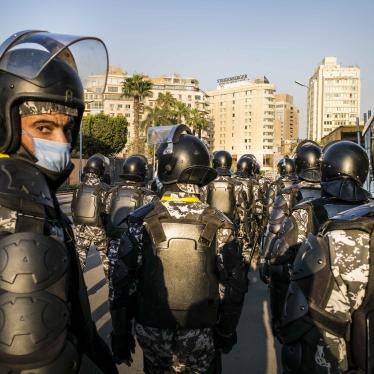 A group of uniformed police with riot gear stand on the street