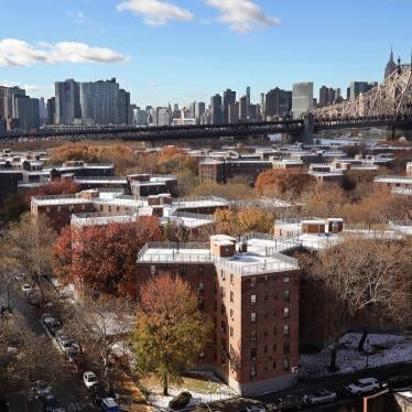 Aerial view of a housing complex with a city skyline behind it