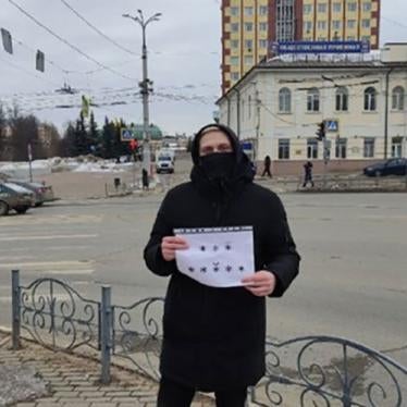 A woman holds a sign while standing at a street corner in Russia