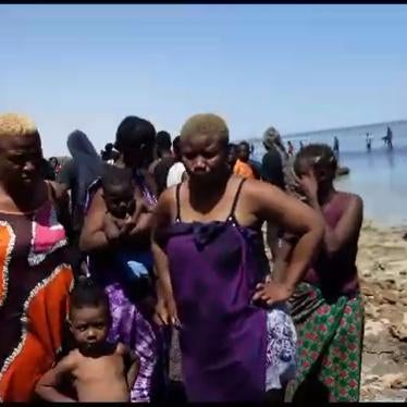Women and children expelled by Tunisian authorities to the Libyan border stand by the shore, July 6, 2023. 