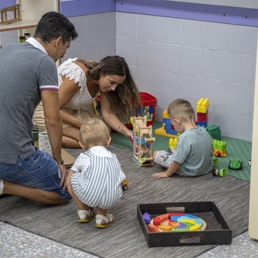 Two parents play with their children at a school in Valencia, Spain, September 12, 2022.