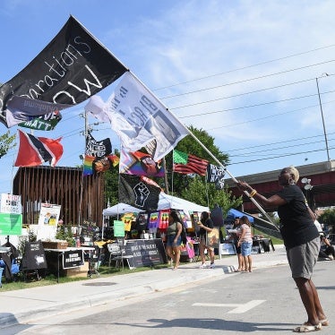 A person waves a flag calling for reparations from the 1921 Tulsa Massacre