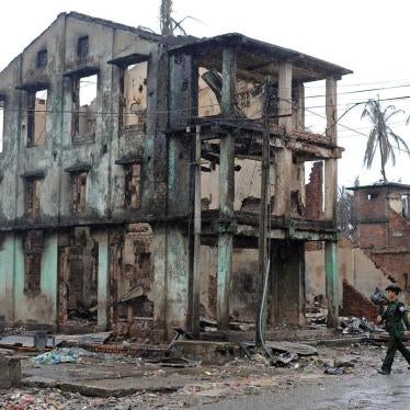 A Burmese soldier walks past a partially destroyed building in Sittwe, capital of Arakan State in western Burma, on June 14, 2012.
