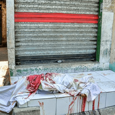 A picture showing a police man standing near a body covered with white cloth.