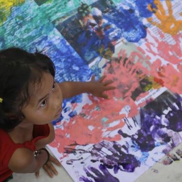 A girl covers anti-LGBT messages in rainbow handprints during a Pride rally in Manila on June 27, 2015.