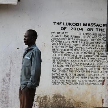 A community member in Lukodi stands next to a memorial of a May 19, 2004 massacre, one of the atrocities for which Dominic Ongwen is facing charges before the International Criminal Court. Over 4,000 victims are participating in the trial. 