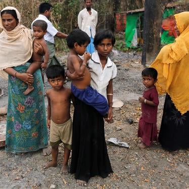 A family stands beside the remains of a burned down market in a Rohingya village outside Maungdaw, Rakhine State on October 27, 2016.