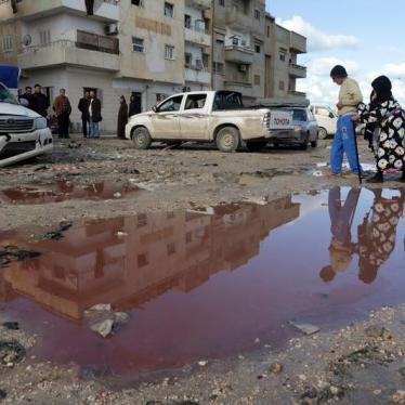 People walk near a puddle of water mixed with blood at the site of twin car bombs near a mosque in the Salmani neighborhood of Benghazi that resulted in scores of deaths and injuries, Libya, January 24, 2018. © 2018 Reuters