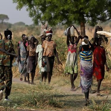 A soldier walks past women carrying their belongings near Benitu, northern South Sudan, February 11, 2017. 