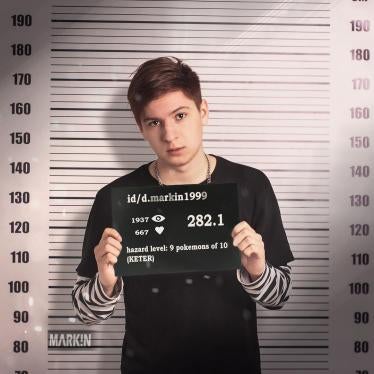 A satirical mugshot depicting Daniil Markin. The nameplate indicates his page on the social media platform VKontake and Russia's Criminal Code Article 282.1 ("incitement of hatred against a religious group"). He faces up to five years in prison under this