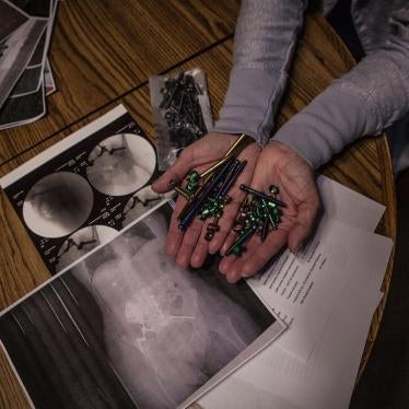 Maria Higginbotham, 57, holding screws and bolts removed from her back in a recent surgery above x-rays of her body.