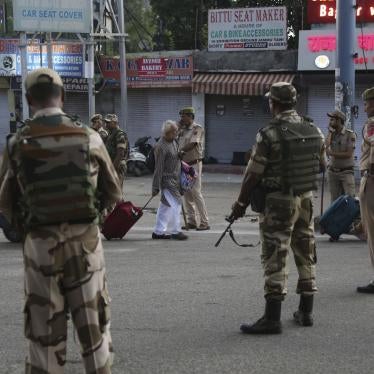 Tourists walk past Indian security forces during curfew like restrictions in Jammu, India, Monday, Aug. 5, 2019. 