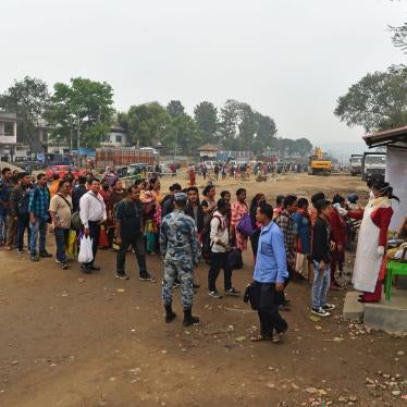 A member of medical staff wearing a facemask amid concerns over the spread of the COVID-19 novel coronavirus, checks the body temperature of travellers arriving from India at the eastern border with Nepal in Kakarvitta, March 14, 2020. 