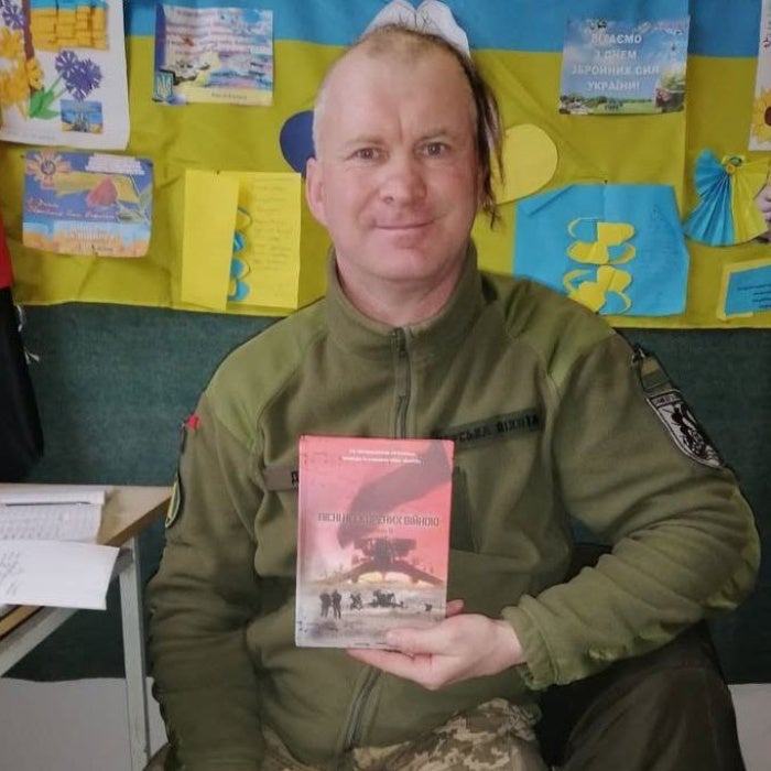 A man poses for a photo holding a book